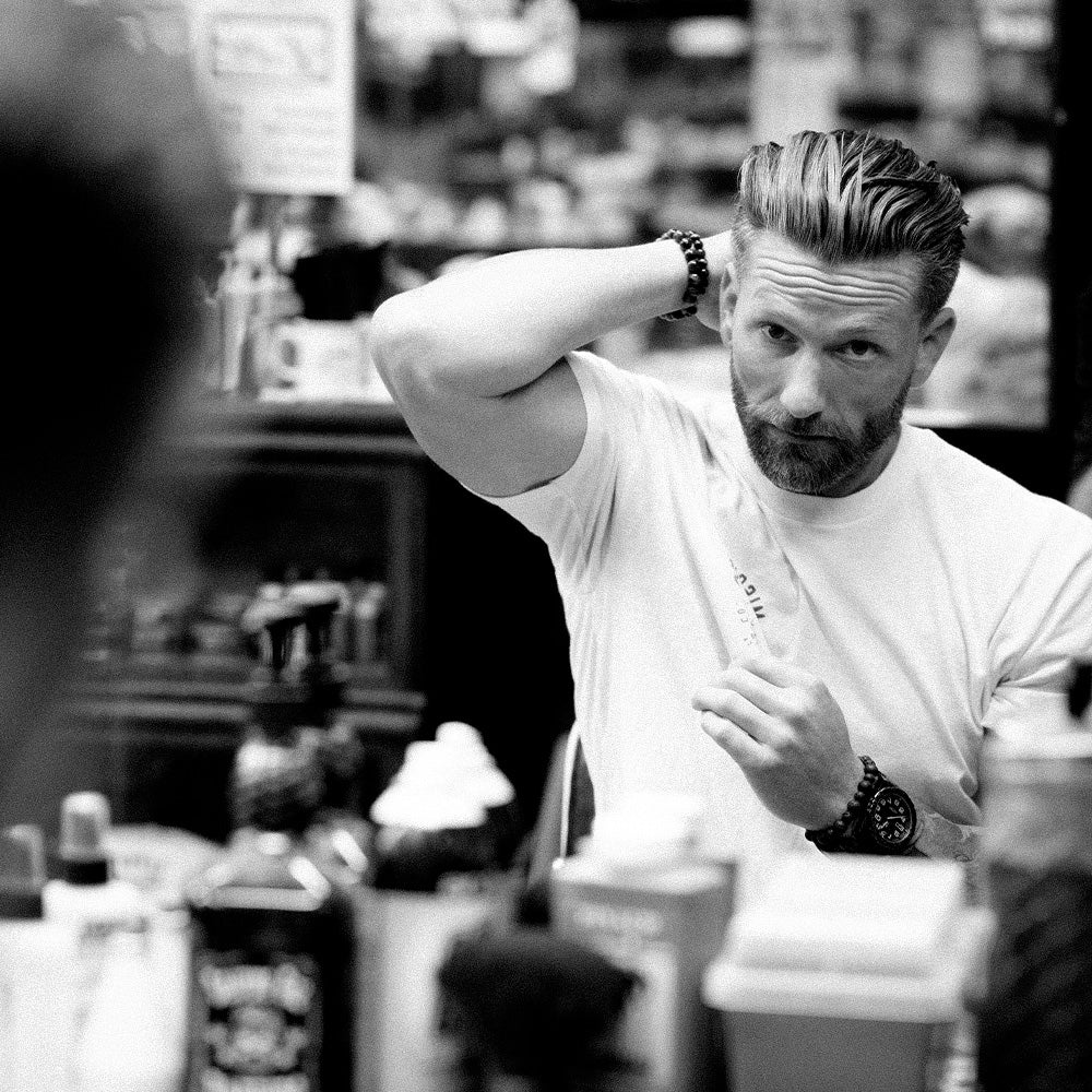 Man styling his own hair in front of mirror