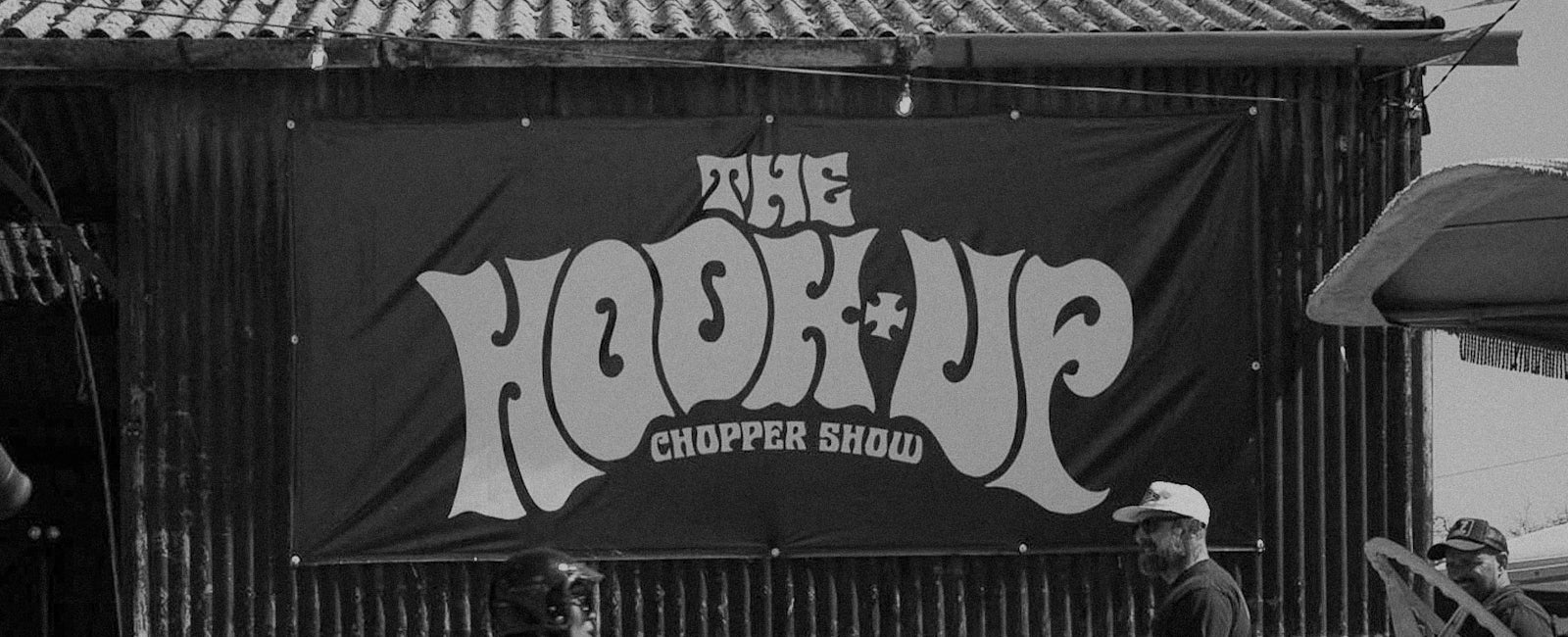 The Hook Up Chopper Show on a banner on the side of a shed with three men standing in front