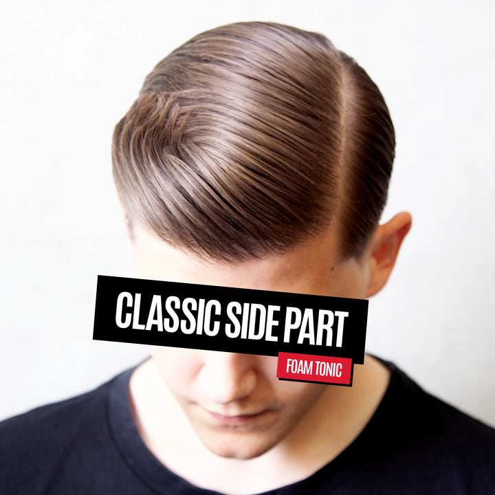 A close-up of a man's head with a styled classic side part hairstyle, showing brown hair with subtle lighter highlights. A black text banner overlays the center with the words 'CLASSIC SIDE PART' and a red label reads 'FOAM TONIC'.