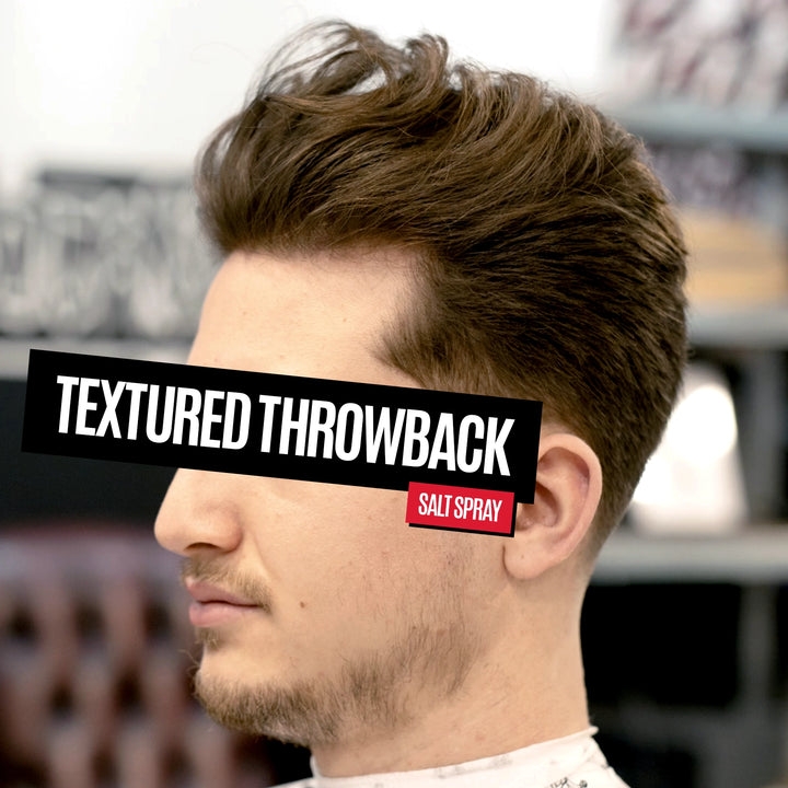A man in profile with styled brown hair and a short fade haircut, wearing a white barber cape. A black banner across the eye reads 'TEXTURED THROWBACK' and a small red badge reads 'SALT SPRAY'.
